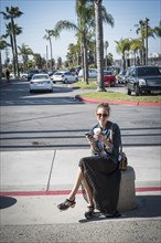 Caucasian woman sitting on concrete barrier in parking lot