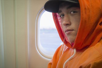 Caucasian man wearing hoodie on airplane