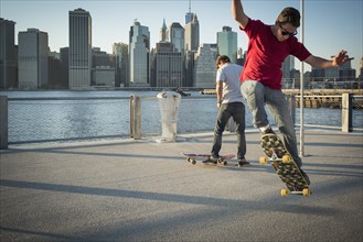 Caucasian skateboarders doing tricks at waterfront