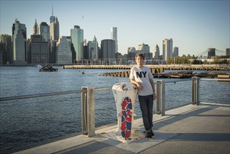 Caucasian skateboarder smiling at waterfront