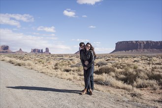 Caucasian couple hugging on desert dirt road