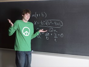 Student shrugging in confusion at chalkboard in classroom