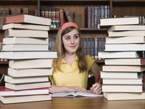 Student with stacks of books at desk in library
