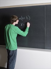 Student writing on chalkboard in classroom