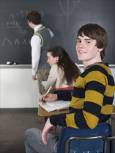 Student smiling at desk in classroom