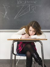 Student writing notes at desk in classroom