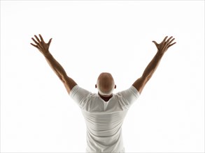Rear view of older man cheering with arms raised