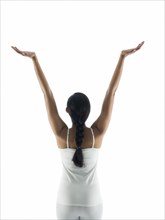 Rear view of woman meditating with arms raised