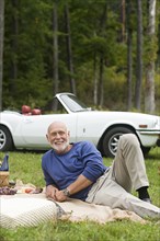 Older man laying on picnic blanket in park