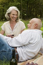 Older couple drinking wine at picnic
