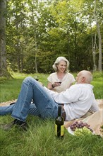 Older couple drinking wine at picnic in park