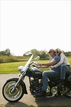 Older couple riding motorcycle on rural road