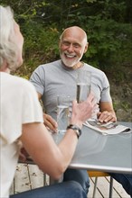Older couple drinking water at table outdoors