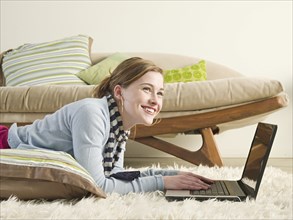 Caucasian woman using laptop on carpet