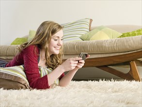 Caucasian woman using cell phone on carpet