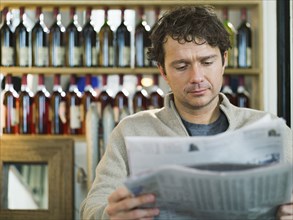 Caucasian businessman reading newspaper in restaurant