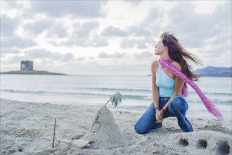 Caucasian woman building sandcastle on beach