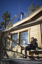 Caucasian woman reading book on cabin porch