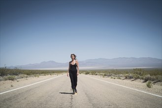 Caucasian woman walking on remote desert road