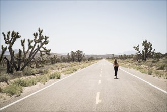 Caucasian woman walking on remote desert road