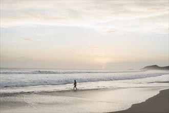 Caucasian woman walking on beach at sunset