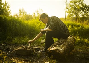 Caucasian man lighting campfire in rural field