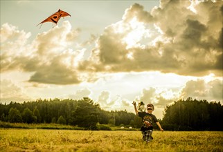 Caucasian boy flying kite in rural field