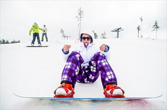 Caucasian snowboarder sitting in snow