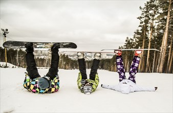 Caucasian snowboarders laying in snow with legs raised