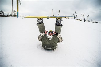 Caucasian snowboarder laying in snow with legs raised