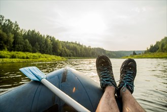 Man resting feet on boat in lake