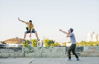 Caucasian men jumping in city