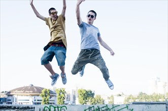 Caucasian men jumping for joy in city