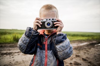 Caucasian boy taking photograph in rural field