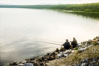 Caucasian men fishing in rural lake