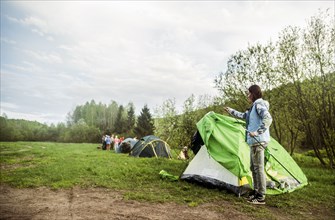 Caucasian camper assembling tent in remote field