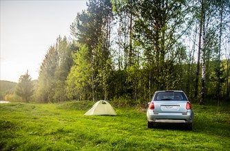 Car and tent at campsite in field