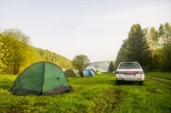 Car and tents at campsite in field