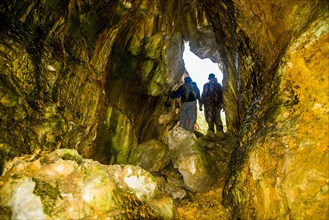 Caucasian men exploring rock formation cave