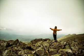 Caucasian hiker with arms outstretched on rocky hilltop