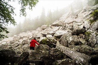 Caucasian hiker climbing rocky hillside