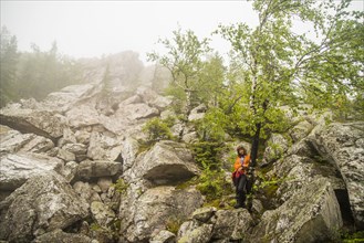 Caucasian hiker standing under tree on rocky hillside