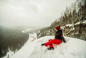 Caucasian hiker sitting on snowy hilltop
