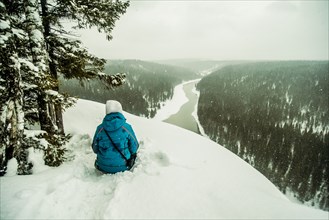 Caucasian hiker sitting on snowy hilltop