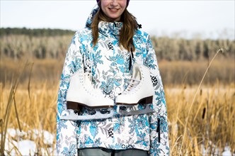 Caucasian woman carrying ice skates in field