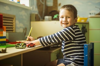 Caucasian boy painting at desk in playroom