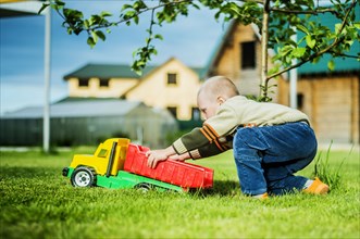 Caucasian boy playing with toy truck in backyard