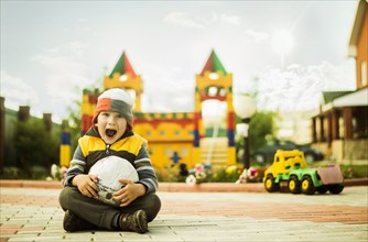 Caucasian boy with mouth open holding ball at playground