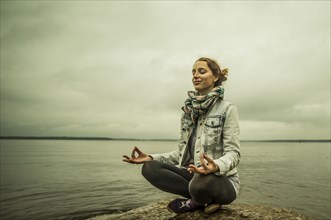 Caucasian woman meditating near ocean