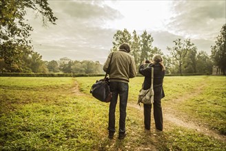 Caucasian couple standing on trail in park with camera